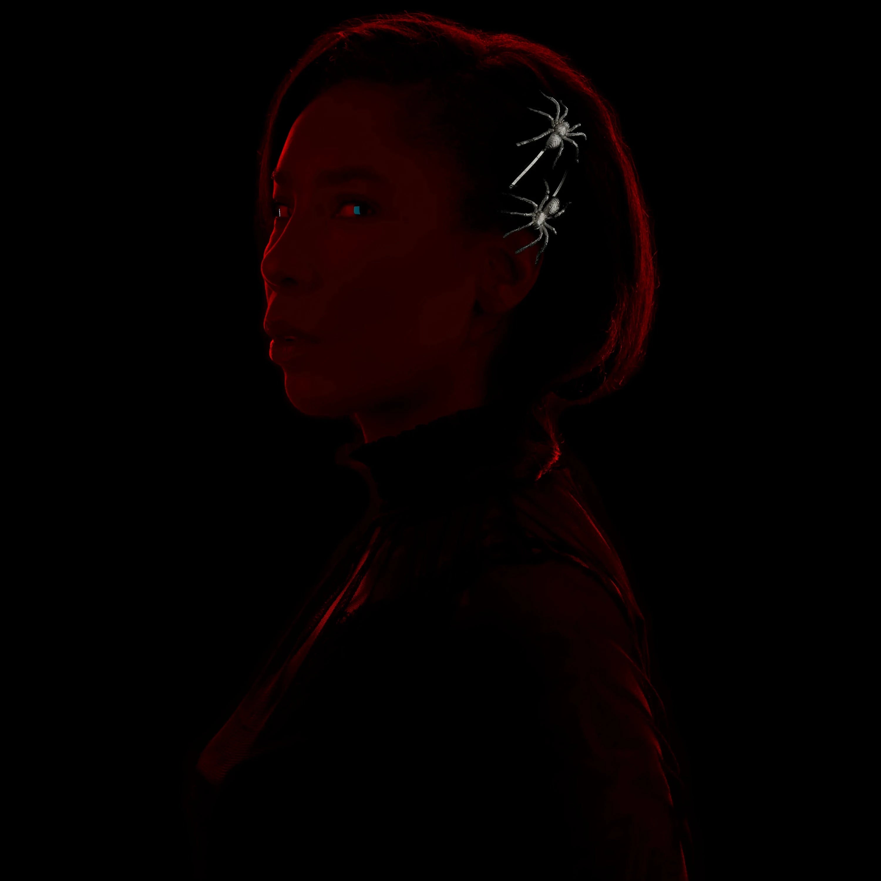 Model wears two rhodium spiders in her hair against a black background.
