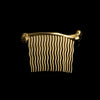 One gold femur bone hair comb with wavy teeth against a black background.