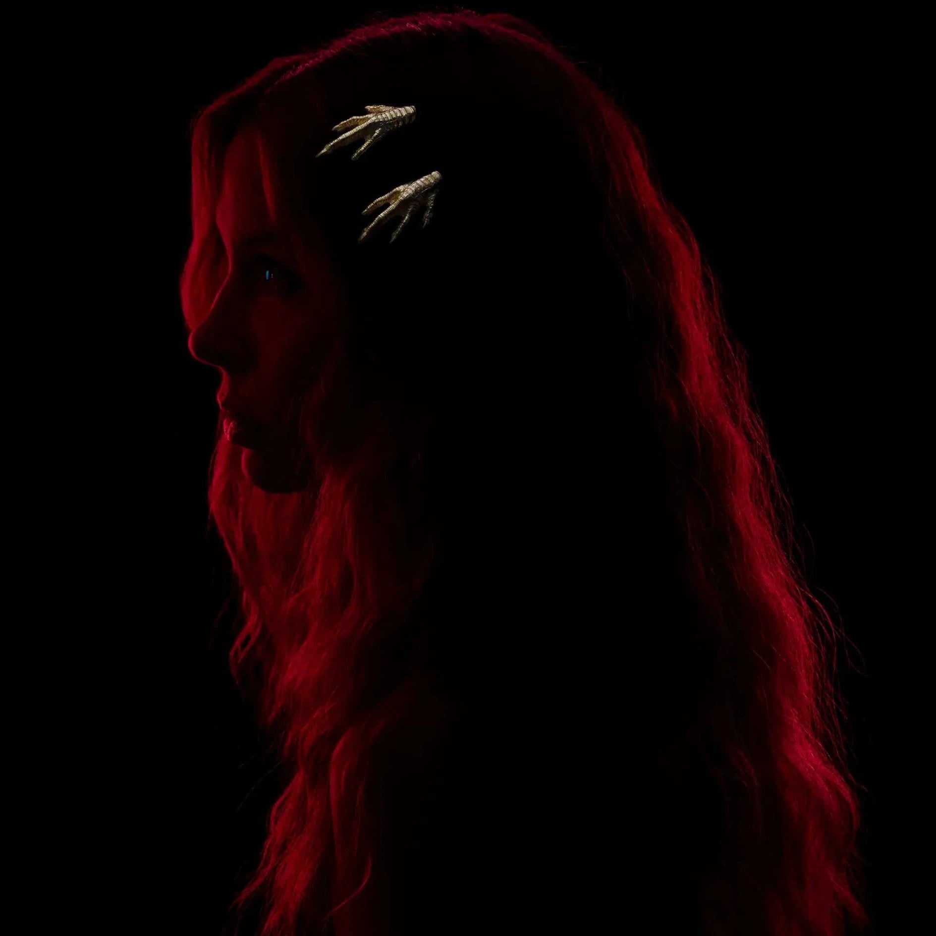Model wears two gold chicken feet hair slides against a black background.