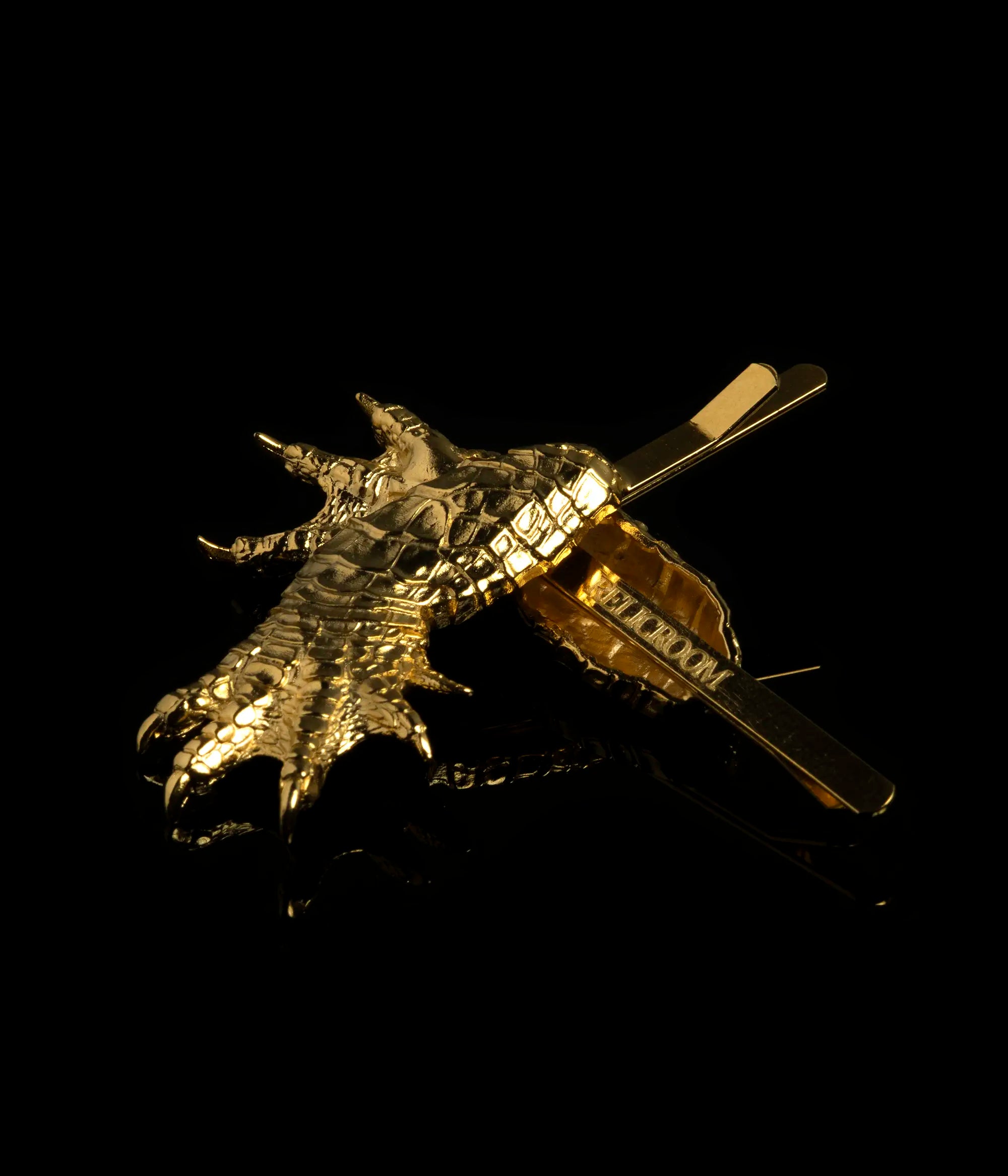 A pair of Gold Alligator Claw Hair Slides with Relic Room logo on the bottom of the hair slide against a black background.