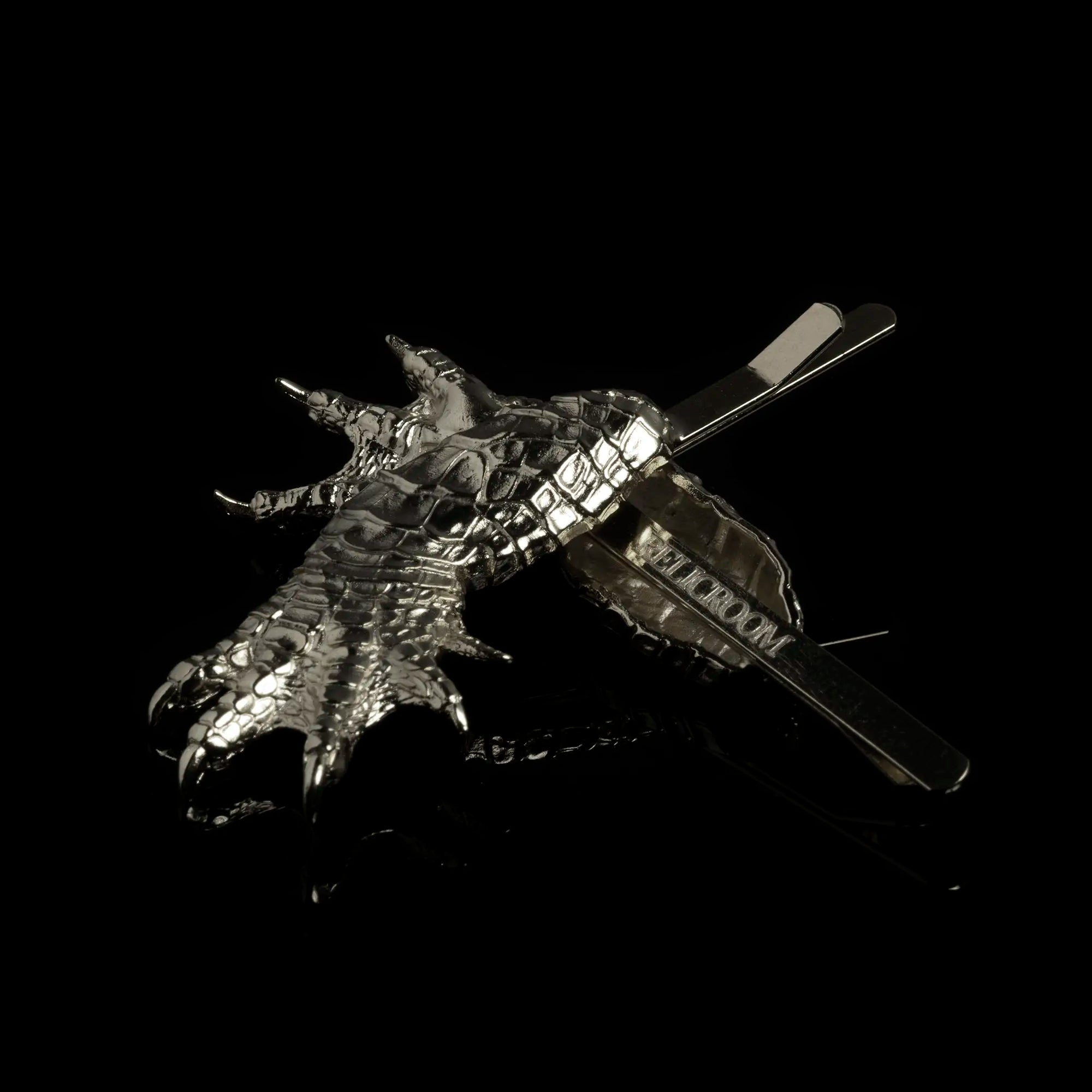 Two mirrored Rhodium alligator claw hair slides featuring Relic Room logo engraved on bottom side of hair accessory against a black background.